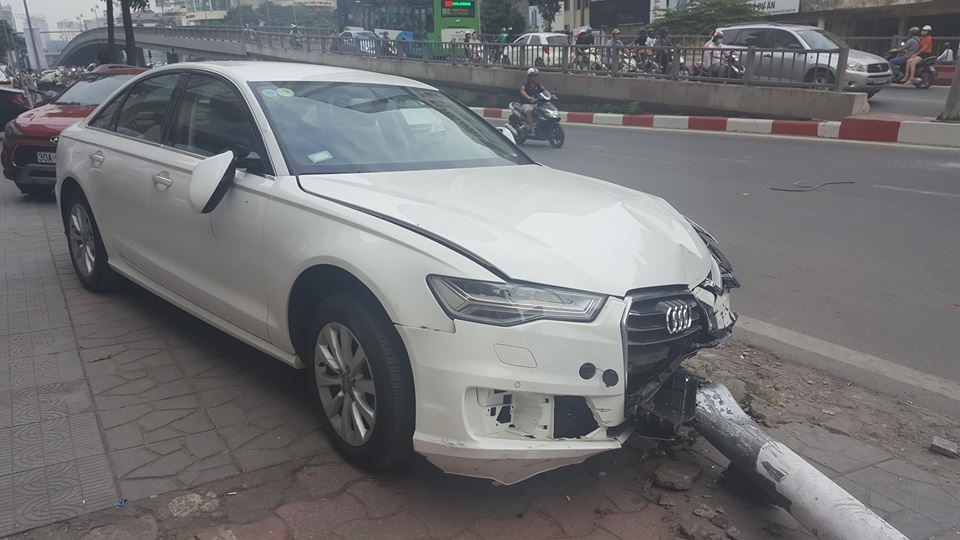 Chiếc xe audi đâm trúng cột đèn, sau đó cột đèn đổ vào một nam thanh niên khiến người này bị thương.