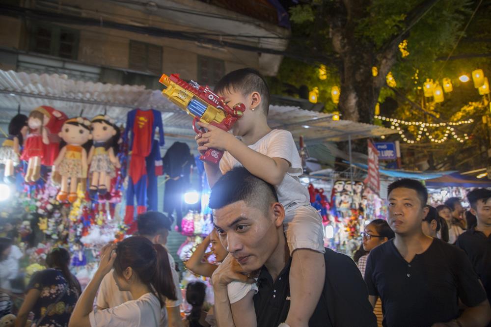 Các em nhỏ thích thú khi được bố kiệu trên vai đi mua sắm Trung thu. Đối với các em, phố Hàng Mã chẳng khác nào “thiên đường đồ chơi” đủ sắc màu, đủ chủng loại, tha hồ chọn lựa.