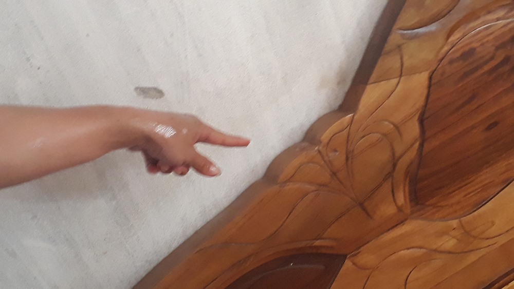 Những vết tích để lại trên tường và làm vỡ một phần gỗ ở đầu giường được cho là đường đi của viên đạn. Ảnh: PV.