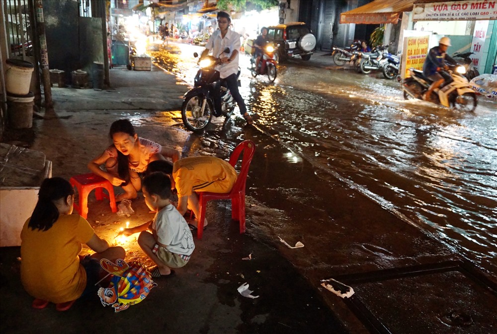 Một nhóm trẻ em mang đèn trung thu, nến ra vỉa hè đường D2 tìm nơi khô ráo chơi trung thu. Ảnh: M.Q