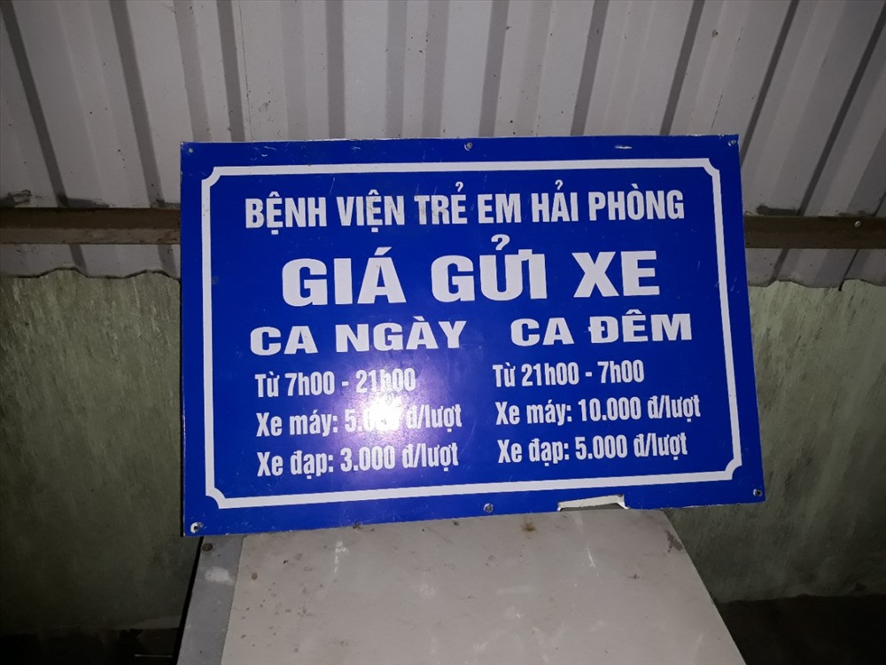 Quy định thu vé gửi xe 10 nghìn đồng/xe được nhân viên giải thích bằng tấm biển cất khá kỹ ở phía sát tường bao - Ảnh TN