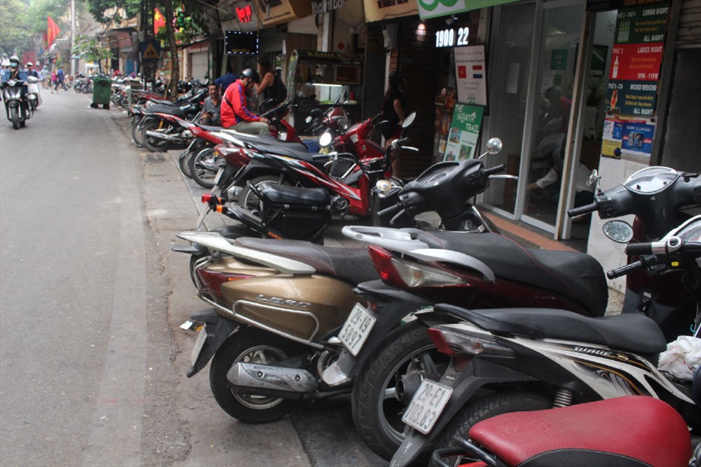 Xe máy dàn hàng ngang, chiếm toàn bộ vỉa hè, buộc người đi bộ phải đi xuống lòng đường.