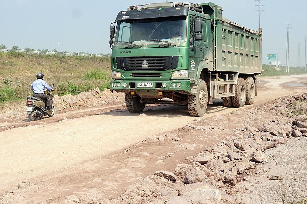 Người điều khiển xe máy, đi lại khó khăn khi phải tránh những xe ben, xe tải và liên tục uốn lượn qua những ổ voi, ổ gà chi chít trên mặt đường