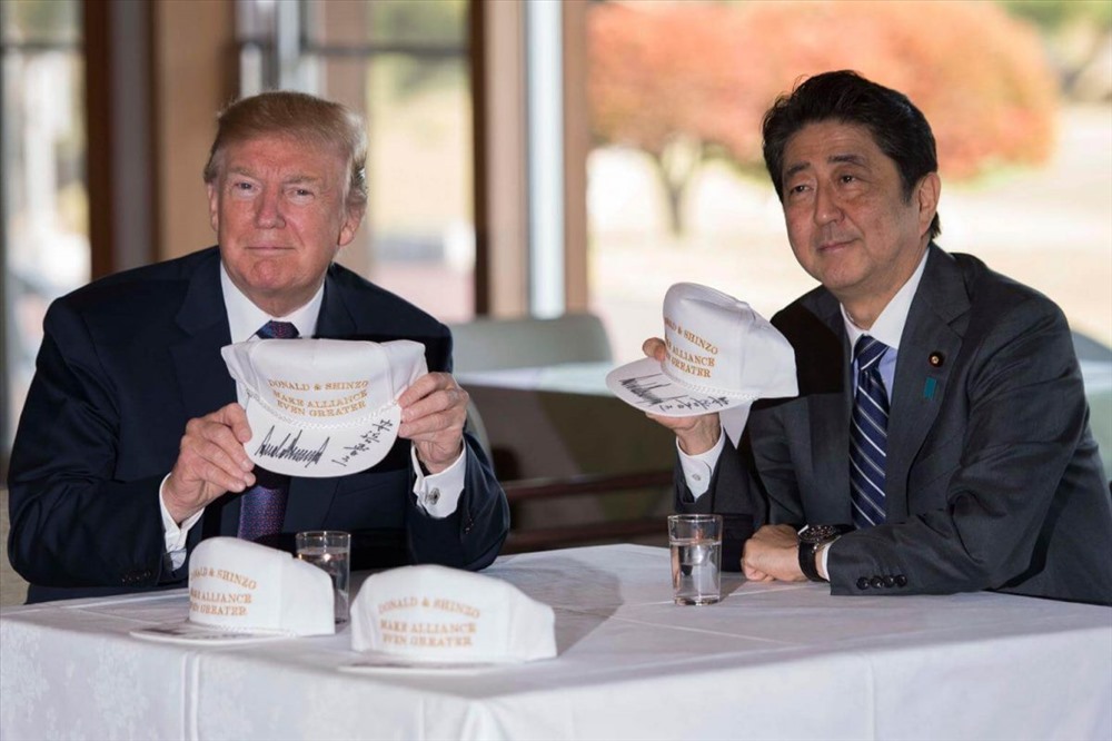 Hai nhà lãnh đạo cầm chiếc mũ in dòng chữ: “Donald và Shinzo: Tạo liên minh lớn hơn“. Ảnh: AFP
