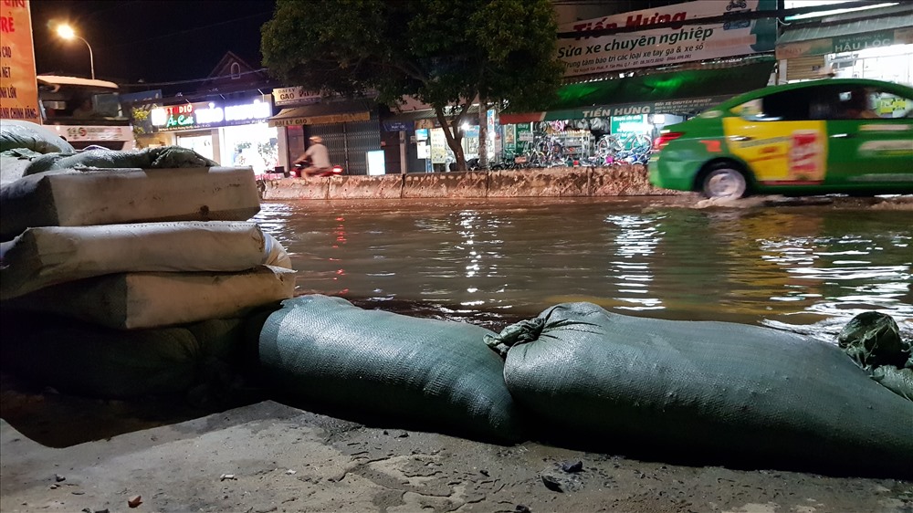 Vốn phải sống chung với ngập biết bao năm nay nên người dân nơi đây coi chuyện nước ngập mỗi khi triều lên là điều đương nhiên và không thể tránh khỏi. Để hạn chế thiệt hại, nước tràn vào nhà, người dân sống dọc con đường này dùng bao cát, ván gỗ để che chắn, nhất là mỗi khi có xe tải chạy ngang qua. Ảnh: Trường Sơn