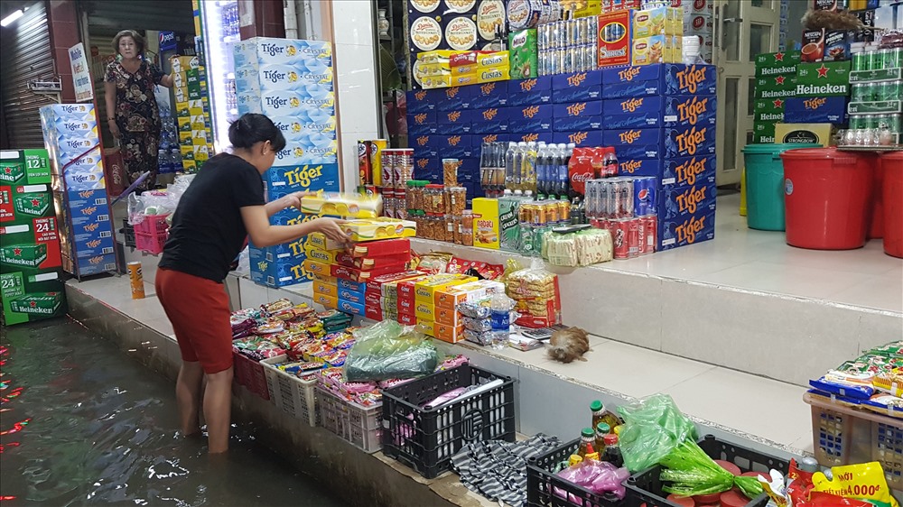 Triều cường không những gây khó khăn trong đi lại, sinh hoạt mà còn khiến tình hình kinh doanh của các hộ dân trên các tuyến đường bị ảnh hưởng nghiêm trọng. trong ảnh là một tiểu thương phải tranh thủ dọn hàng sớm để tránh con nước đang lên. Ảnh: Trường Sơn
