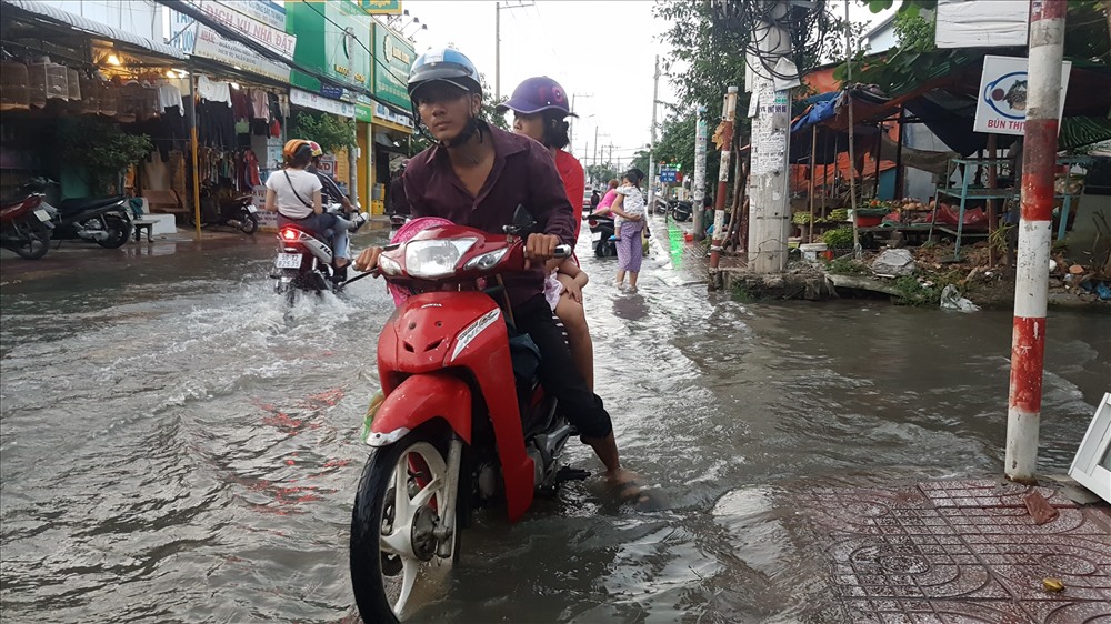 Dù thường xuyên đi qua con đường này mỗi ngày nhưng rất nhiều người dân đã phải lâm cảnh bì bõm cùng chiếc xe máy của mình giữa dòng nước đen xì, bốc mùi nồng nặt bên dưới. Người dân sống dọc đường Lê Văn Lương cho biết, dù cách trung tâm thành phố chừng vài km nhưng họ hàng ngày vẫn phải “sống chung với ngâp” suốt hàng chục năm nay và trước mắt vẫn chưa thấy lối thoát khỏi tình trạng này. Ảnh: Trường Sơn