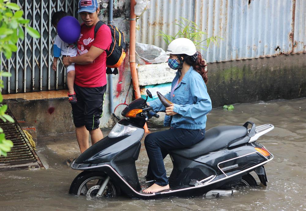 Bố phải ẵm con để mẹ lái xe qua đoạn đường ngập nặng. Ảnh: Trường Sơn