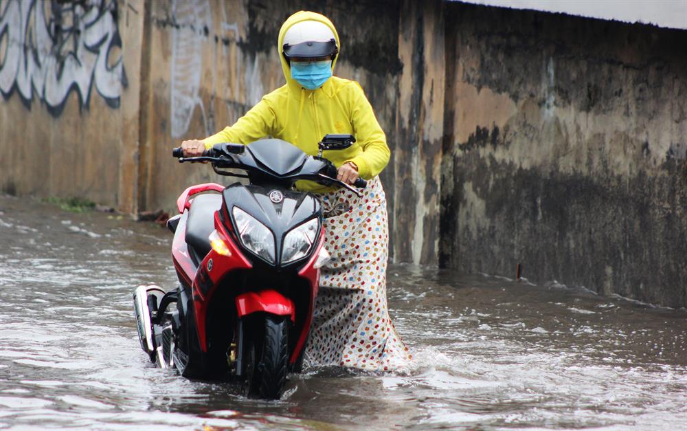 Xe bị chết máy, cô gái này phải bì bõm lội qua dòng nước để đến sở làm. Ảnh: Trường Sơn