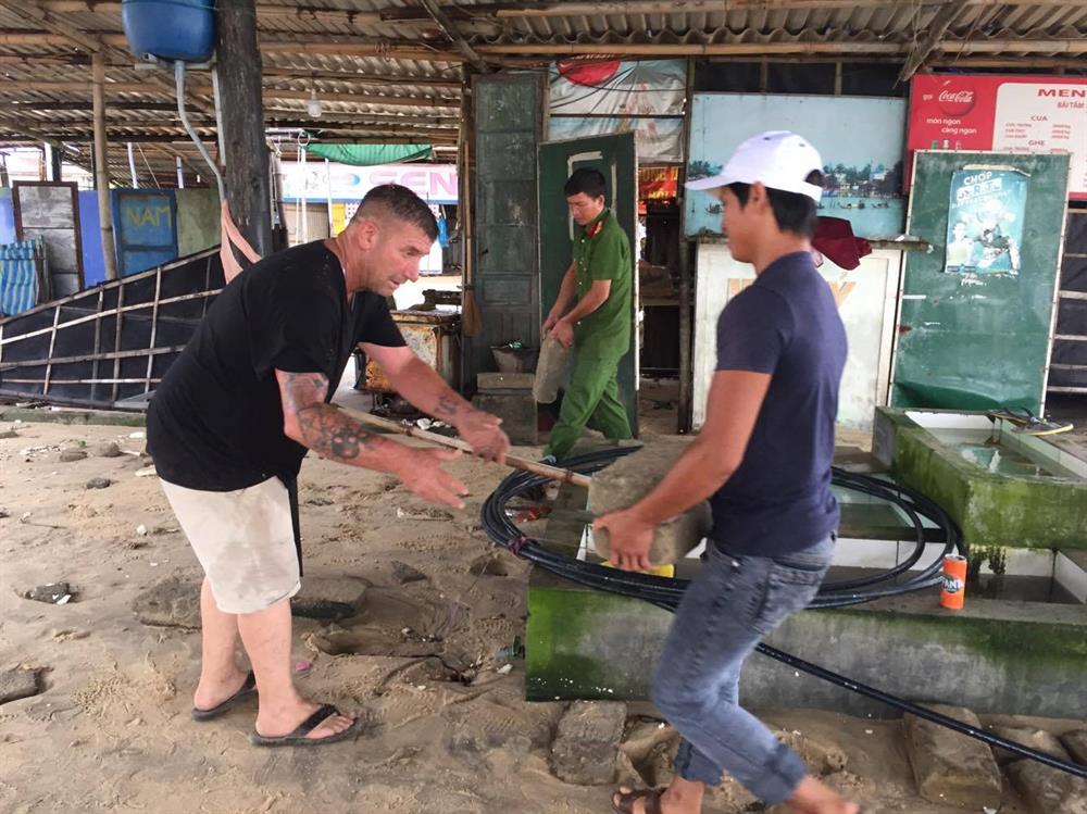 Công an, và cả cả người nước ngoài cũng giúp người dân đối phó với bão số 10. Ảnh: Đắc Thành.