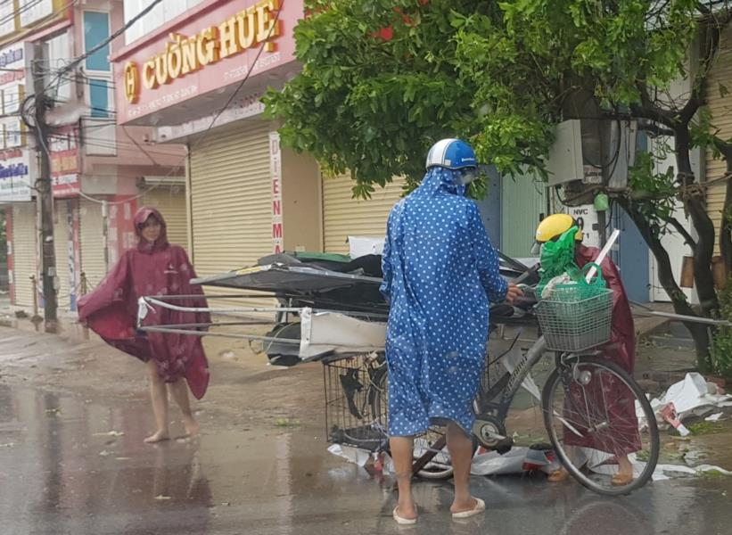 Người dân dọn dẹp những tấm tôn và vật dụng bay xuống đường.Ảnh: Lê Phi Long