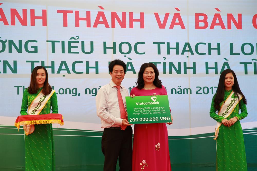 Ông Nguyễn Mỹ Hào – Ủy viên HĐQT Vietcombank (thứ 2 từ trái sang) trao tượng trưng số tiền 200 triệu đồng tài trợ trang thiết bị phòng học cho Trường Tiểu học Thạch Long (Hà Tĩnh)