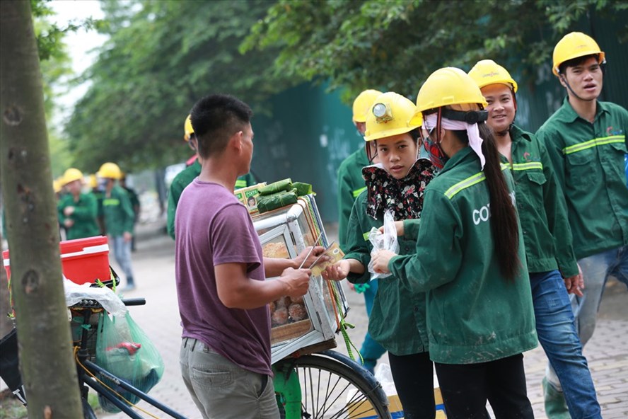 Công nhân xây dựng mua đồ ăn sáng trên đường Phạm Hùng (Hà Nội). Ảnh: HẢI NGUYỄN 