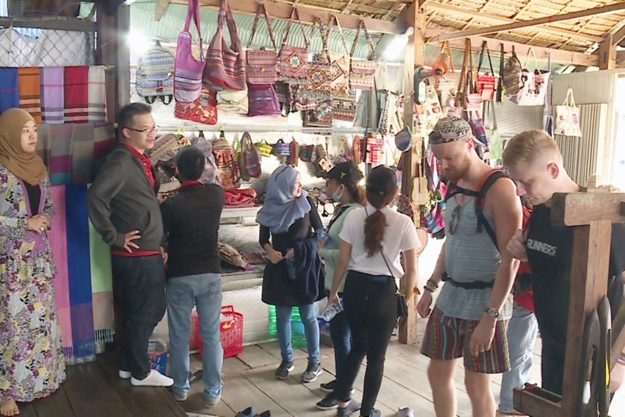 Safinah (trái) giới thiệu các sản phẩm truyền thống của gia đình với khách nước ngoài. Ảnh: DẠ THẢO