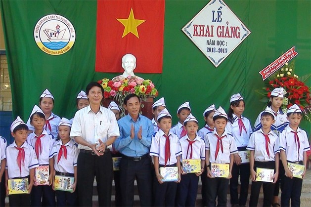 Chủ tịch LĐLĐ tỉnh Quảng Ngãi Trần Quang Tòa và Chủ tịch LĐLĐ huyện Đức Phổ Huỳnh Văn Lang trao tặng vở cho học sinh.