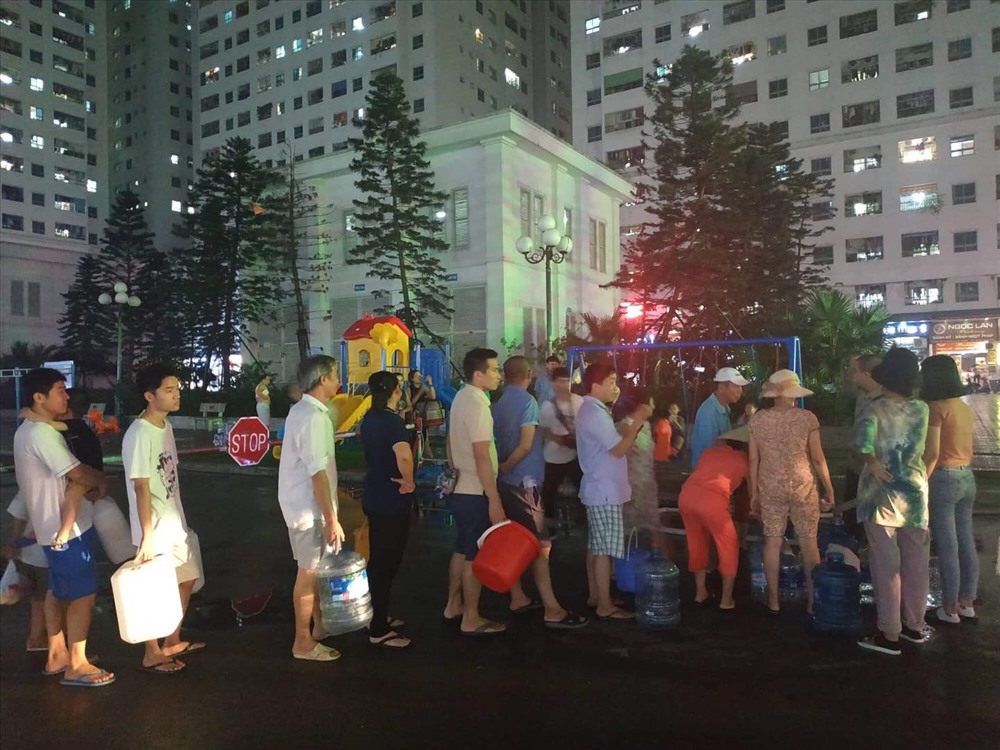 Cư dân HH Linh Đàm xếp hàng chờ phát nước sạch miễn phí tối 16.10. Ảnh: Ngọc Lan