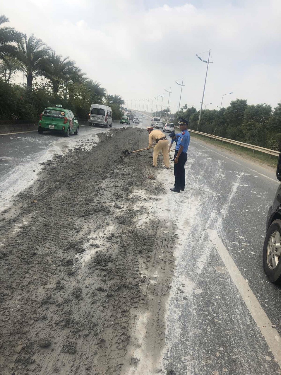 Cảnh sát giao thông và Thanh tra giao thông thu dọn bùn đất trên đường Võ Nguyên Giáp, Hà Nội. Ảnh: PV