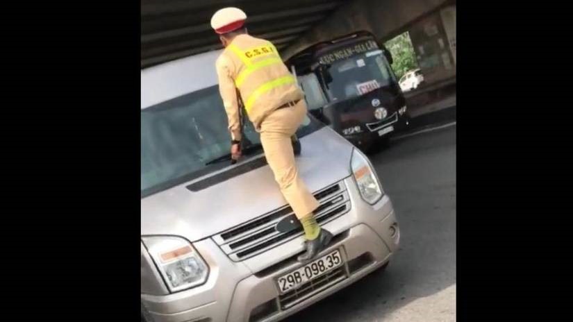 Cảnh sát giao thông phải nhảy lên đầu xe, túm cần gạt nước để đảm bảo an toàn. Hình ảnh cắt từ clip sự việc.