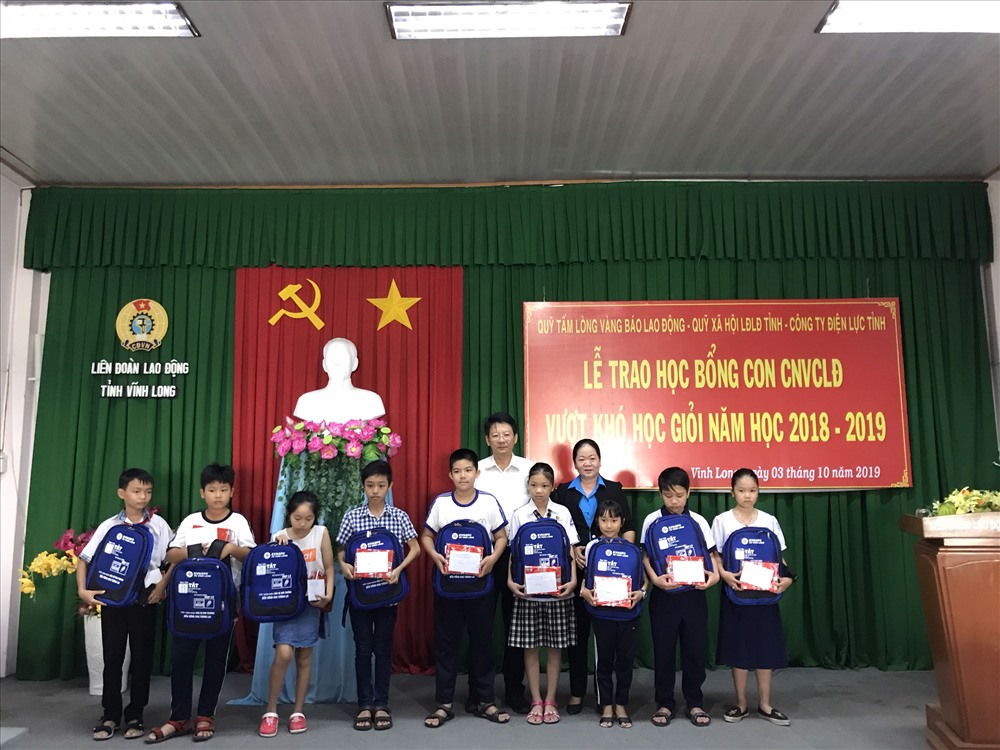 Các em học sinh nhận học bổng và các phần quà từ lãnh đạo LĐLĐ tỉnh Vĩnh Long. Ảnh: B.T