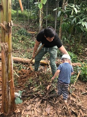 Cháu Duy luôn quanh quẩn bên Alfred khi anh trồng cây mít trong vườn. Ảnh: NVCC