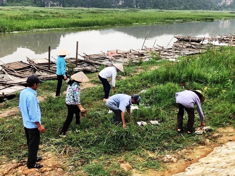 Nhân viên lái đò tại Khu du lịch Đầm Vân Long dọn rác tại khu vực bến thuyền. Ảnh: Nguyễn Trường