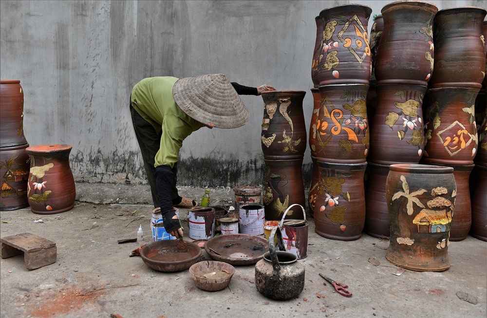 Vá lại những vết xước, vỡ trong lòng bình gốm. Người phụ nữ này cho biết thu nhập một ngày 8 giờ chỉ từ 150.000 - 180.000 đồng, chỉ có thợ vẽ là cao nhất khoảng 250.000 đồng.
