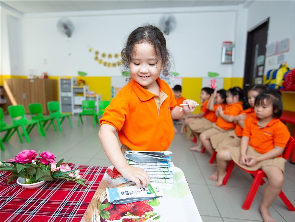 Các em học sinh hào hứng uống sữa và gấp vỏ hộp sữa sau khi uống theo sự hướng dẫn của cô giáo.