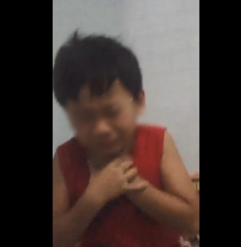 Sau khi uống hết ly rượu cháu tím tái mặt mày, ôm cổ vì đắng cay. Ảnh cắt từ clip.