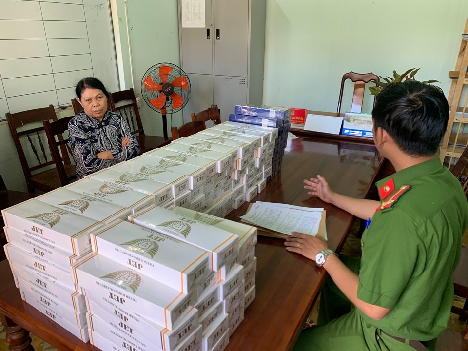 Bà Huệ bên cạnh hàng nghìn bao thuốc lá lậu bị lực lượng chức năng thu giữ. Ảnh; Công an cung cấp.