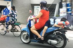 Đứng tim trước cảnh đứa trẻ nằm dài trên yên xe máy