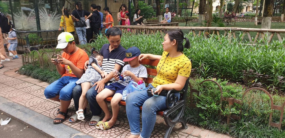 Một gia đình ngồi nghỉ ngơi tại ghế công viên.