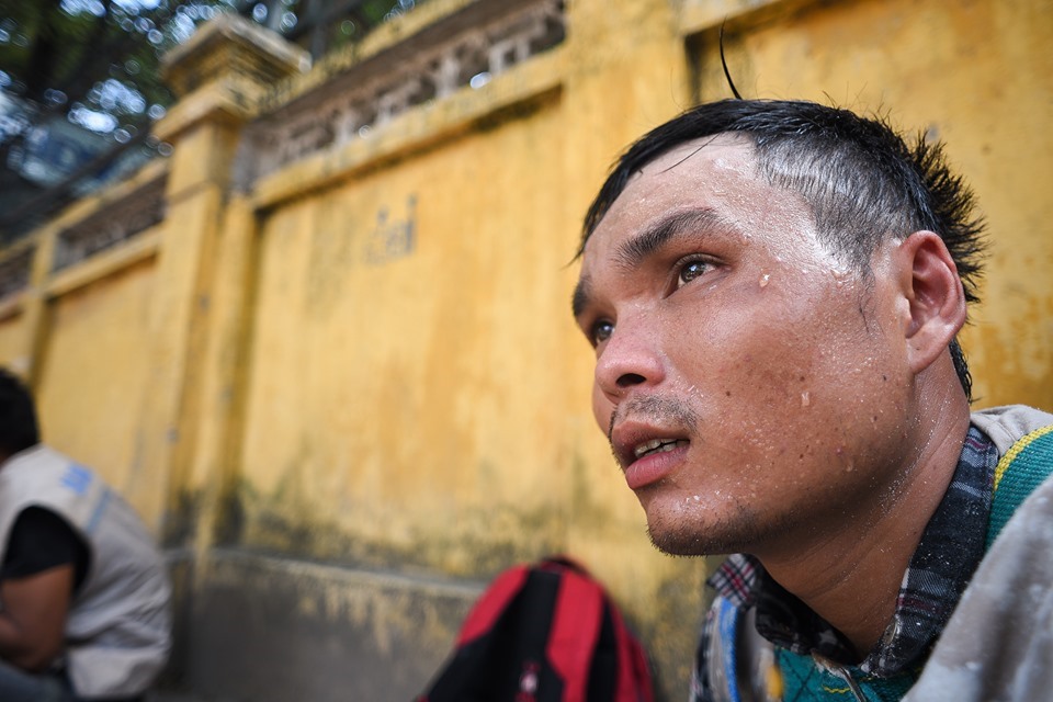 Một người đàn ông mướt mồ hôi, ngồi nghỉ tạm bên đường trong cái nắng như thiêu như đốt.