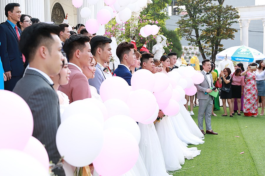 Cô dâu, chú rể chụp ảnh cưới tập thể ngoài trời.