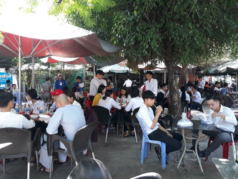 Thí sinh nhận cơm từ các TNV ăn vội để kịp ôn bài. Ảnh: Hồng Lan