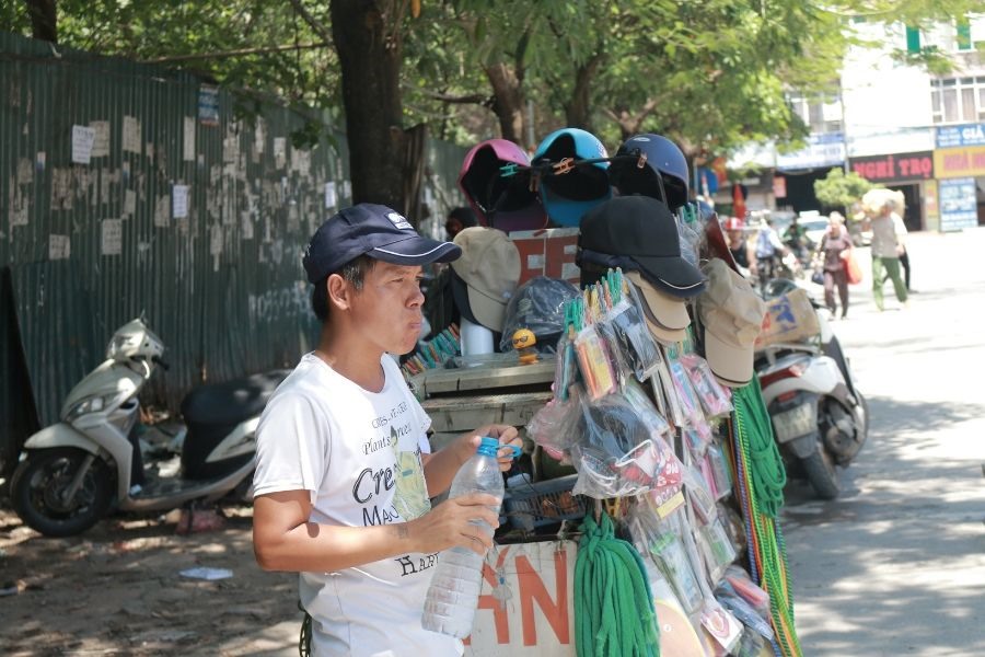 Người bán hàng rong tranh thủ ăn bữa trưa đạm bạc tại vỉa hè phố Nguyễn Chánh (Quận Cầu Giấy).