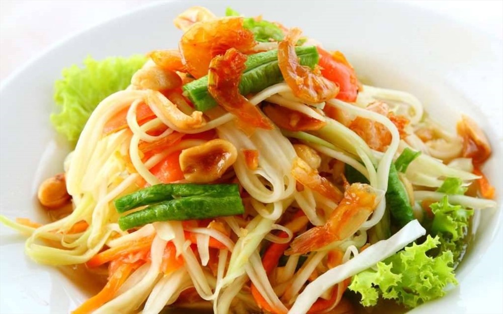 4. Som Tum Thái (Nộm đu đủ): Nguyên liệu của Som Tam gồm đu đủ sợi, ớt, tôm khô, cà chua, đậu đũa bẻ nhỏ. Tất cả được cho vào cối giã, sau đó thêm cốt chanh, nước mắm, đường thốt nốt rồi trộn cho gia vị thấm đều vào đu đủ. Ảnh: Vietnamtourist