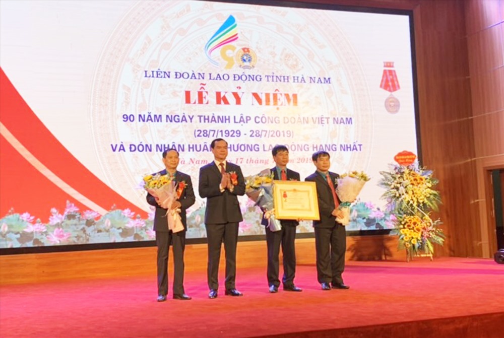 Đồng chí Nguyễn Đình Khang - Uỷ viên TƯ Đảng, Bí thư Tỉnh uỷ Hà Nam (thứ hai từ trái sang) trao Huân chương Lao động hạng Nhất cho LĐLĐ tỉnh Hà Nam. Ảnh: Thu Lệ