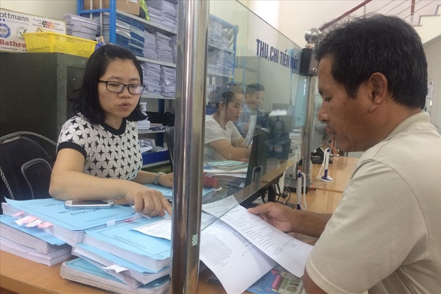 Cán bộ BHXH quận Hà Đông hướng dẫn người dân làm thủ tục liên quan đến chế độ BHXH. Ảnh: Quế Chi