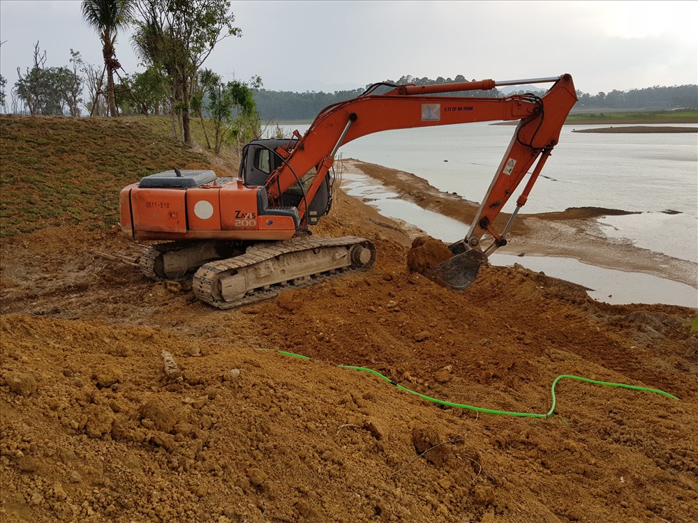 Máy xúc được huy động múc phần đất lấn chiếm xuống hồ Đồng Mô tại khu đồi Mơ.