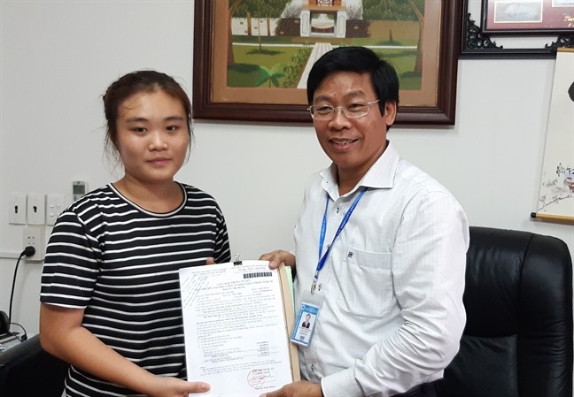 Phó giáo sư - tiến sĩ Nguyễn Xuân Hoàn - Phó Hiệu trưởng Trường Đại học Công nghiệp Thực phẩm TP.HCM trao quyết định miễn học phí năm học đầu tiên cho Gia Hân. Ảnh: Tinh Châu