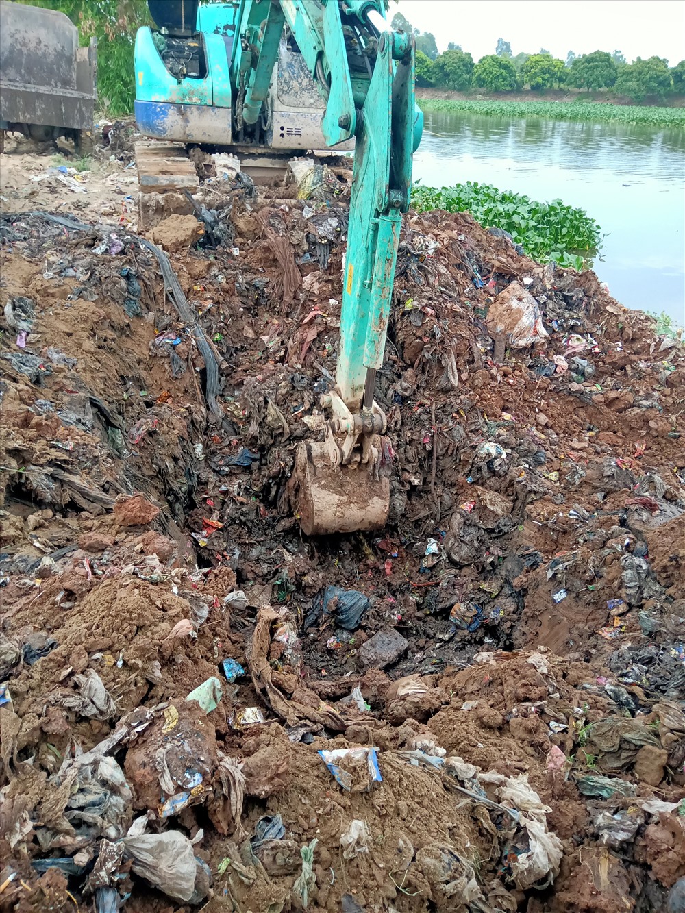 Rác thải được chôn lấp ở thân đê, sát mép sông thôn Viên Quang được đưa vào nơi tập kết. Ảnh: QTL.