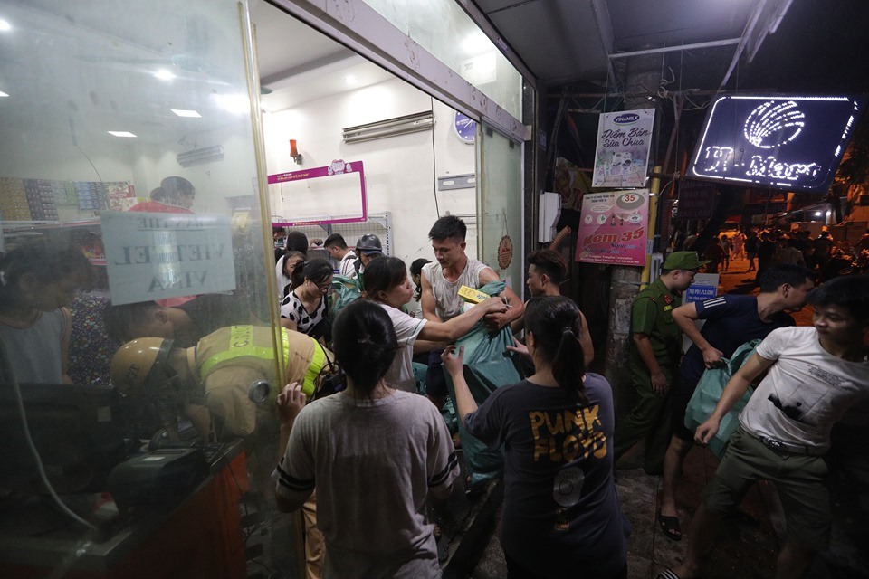 Người dân và cơ quan chức năng hỗ trợ những nhà bị cháy mang đồ đạc ra ngoài.