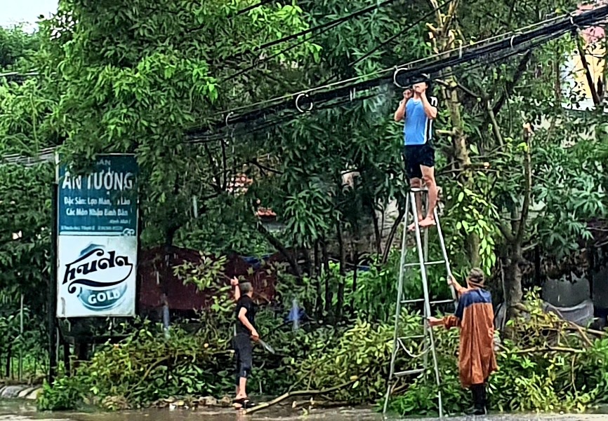 Người dân tự chặt bớt các cành cây nhằm bảo đảm an toàn. Ảnh: Lê Phi Long