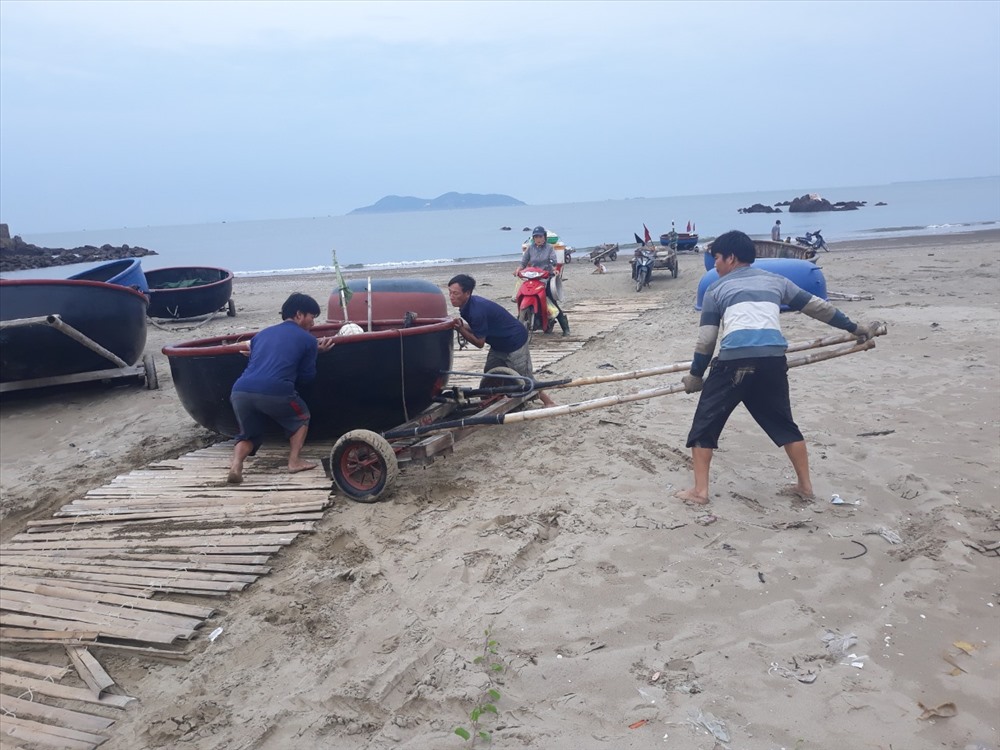 Ngư dân hợp sức đưa thuyền thúng lên bờ. Ảnh: PV