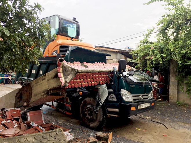 Cổng chào bị kéo đổ và đè sập cabin. Ảnh: V.Đ.