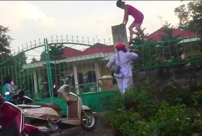 Nhân viên Trung tâm nhân đạo vượt rào chuyển quà từ thiện ra bên ngoài. Ảnh: Nguyễn Long.