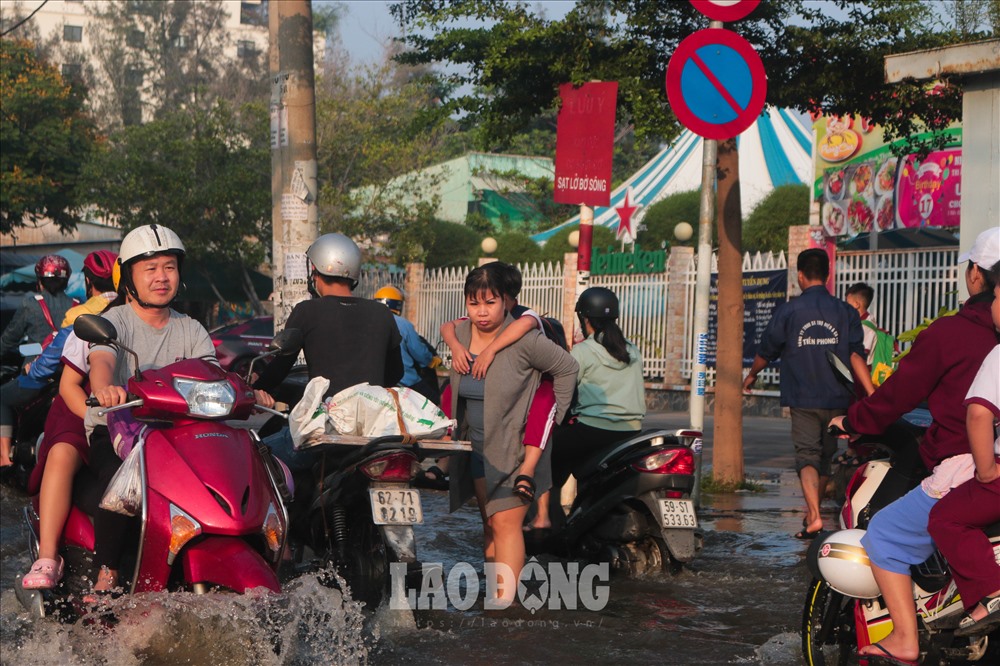 Nhiều phụ huynh bì bõm đưa con đi học.