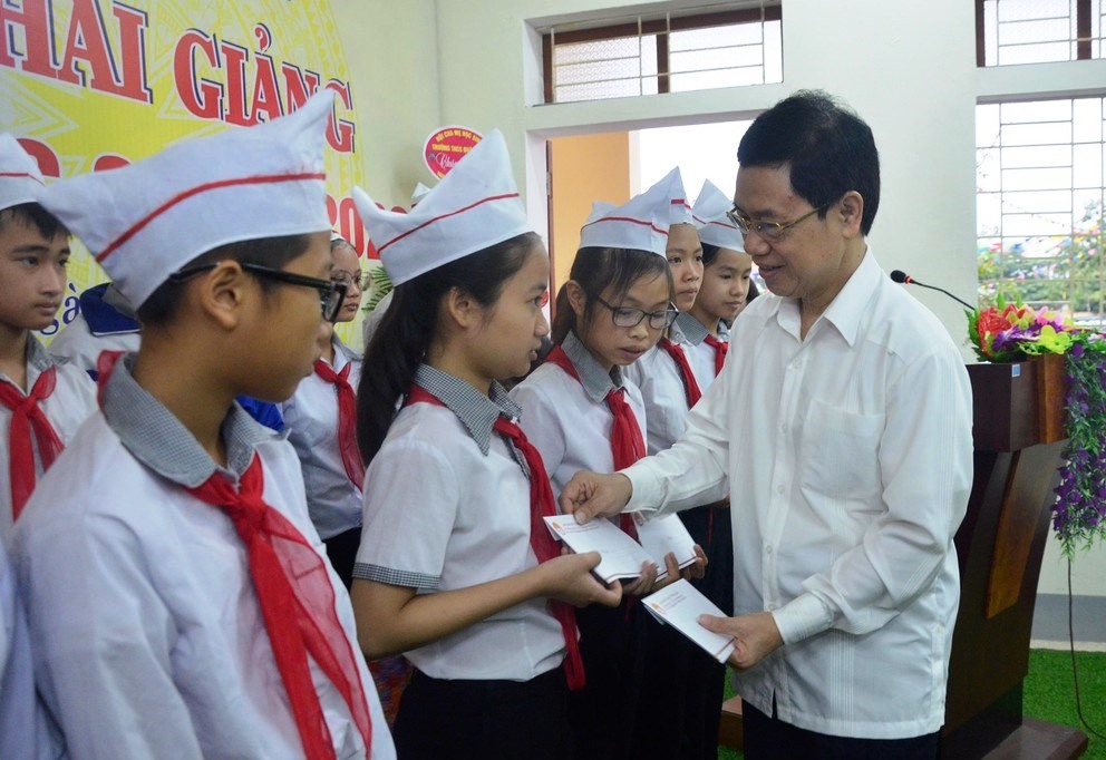 Ông Nguyễn Xuân Sơn - Phó Bí thư thường trực Tỉnh ủy - Chủ tịch HĐND tỉnh Nghệ An tặng quà khai giảng cho học sinh trường THCS Quán Hành (huyện Nghi Lộc). Ảnh: T. Lê