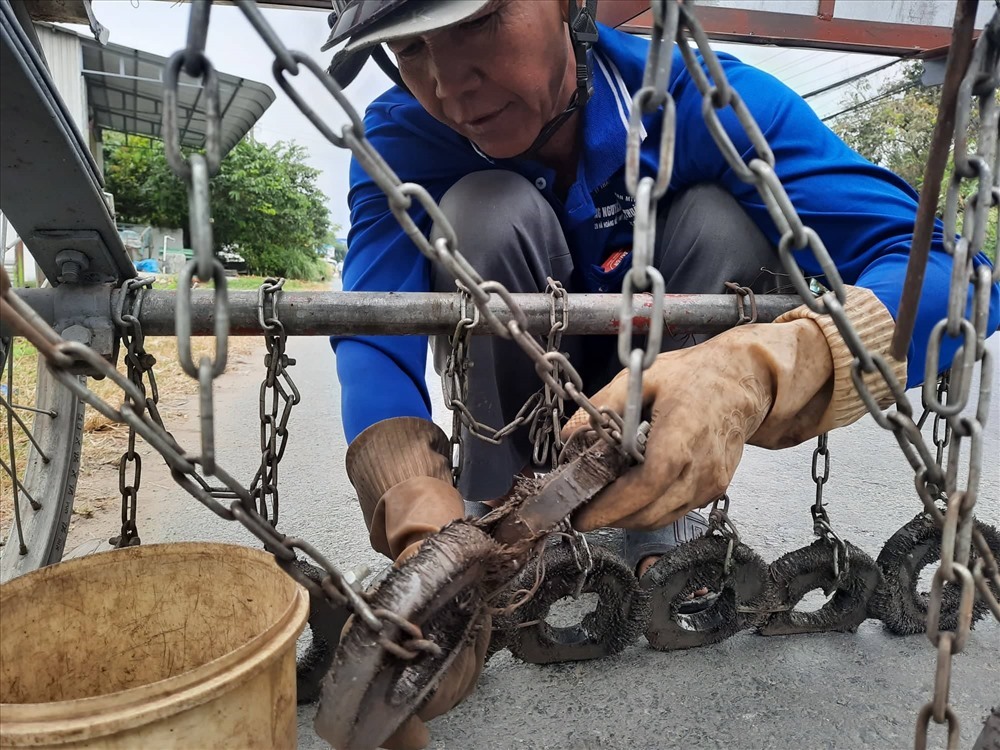 Ông Năm Sang đang lấy bớt đinh và sắt vụn ra khỏi cục nam châm. Ảnh: P.T