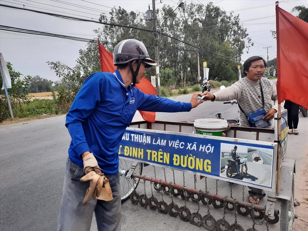 Một người đi đường dừng lại ủng hộ chi phí tiền xăng cho ông Năm Sang. Ảnh: P.T